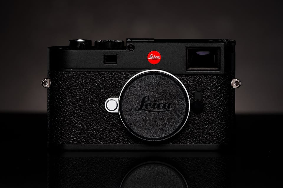 Leica M11 body with cap, dead-on front view in dark studio lighting